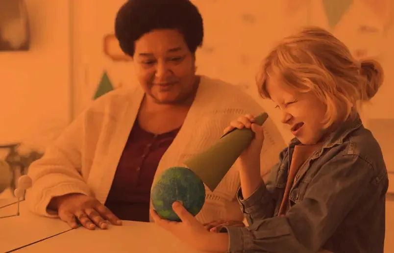 A teacher and a child looking at a globe together